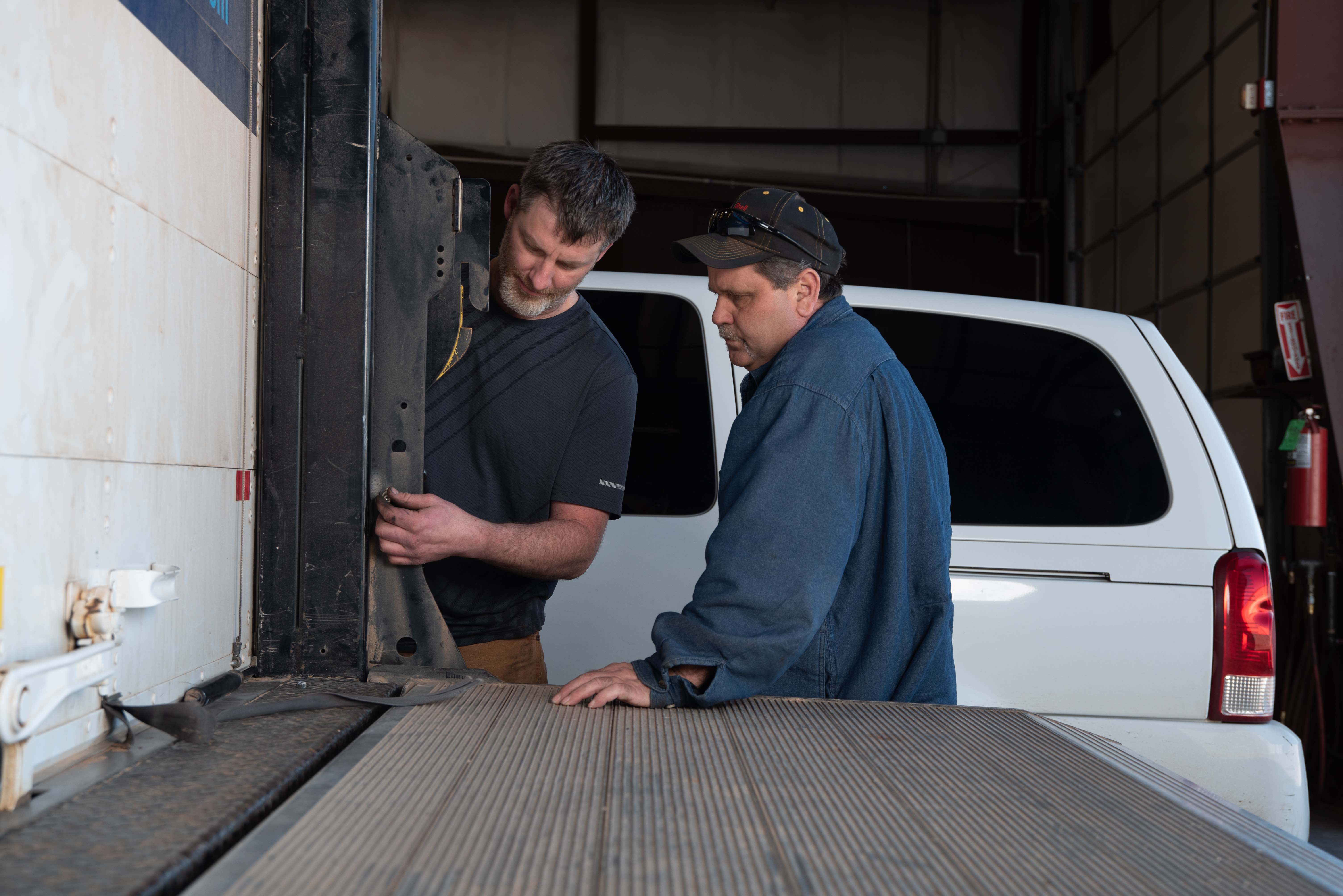 two men evaluate truck door and lift gate